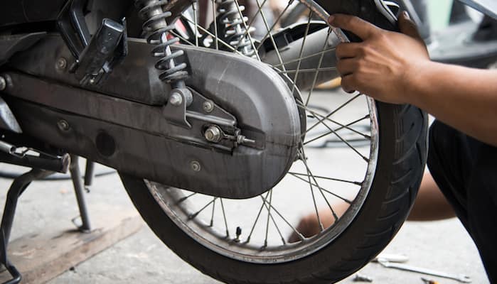 Mechanic's hand on rear tire of motorcycle prior to changing it