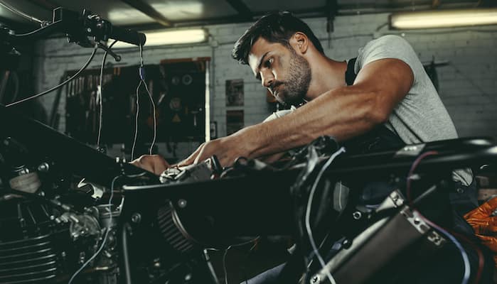 Mechanic working on servicing motorcycle in repair shop